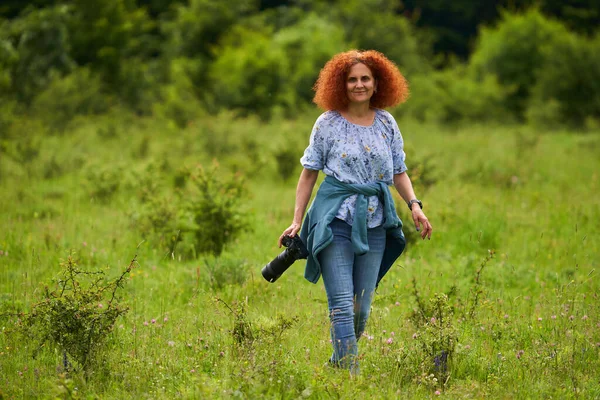 野外草地上拿着相机的自然女摄影师 — 图库照片