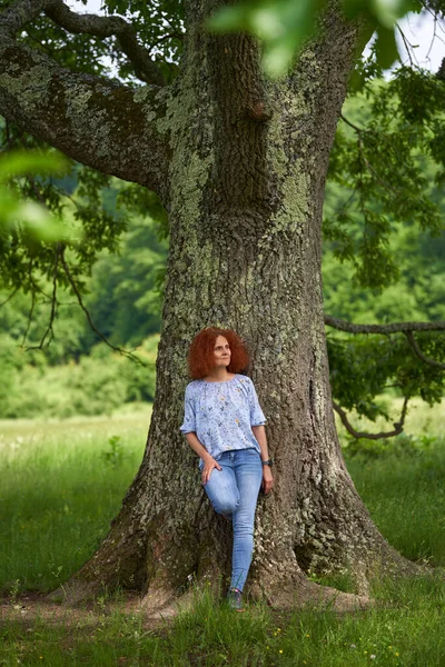 オークの森の牧草地に立つ赤毛の女の肖像 — ストック写真