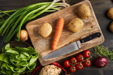 Tahta bir tahtanın üzerinde taze çiğ sebzelerden oluşan düz bir atış.