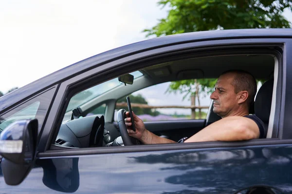 Man Sms Mobiele Telefoon Achter Het Stuur Van Zijn Auto — Stockfoto