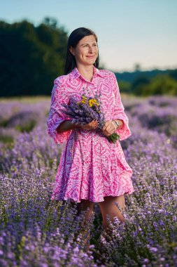 Çiçek açan lavanta tarlasında çekici esmer bir genç kadın.