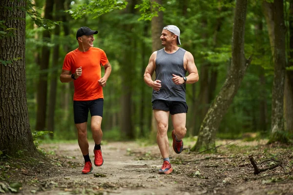 两个男人朋友在一条小径上跑过森林 — 图库照片