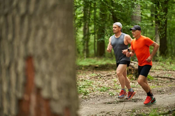 2人の男性の友人が森の中を走るトレイルで一緒に走る — ストック写真