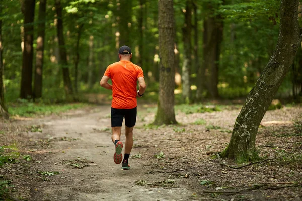 一个高加索人在穿过森林的小径上慢跑 — 图库照片