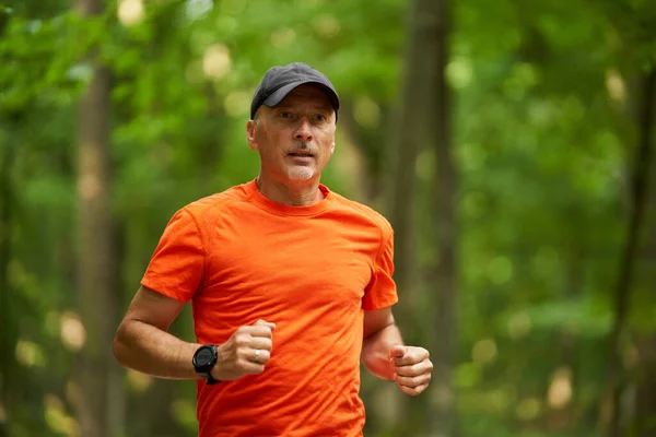 A caucasian man jogging on a running trail through the forest