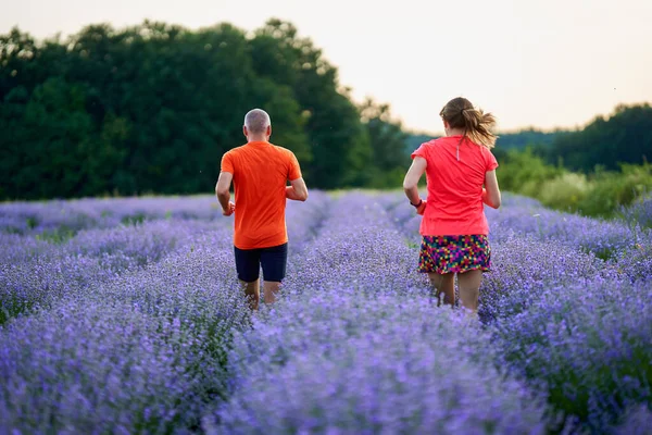 Paar Hardlopers Joggen Een Lavendelplantage Bij Zonsondergang — Stockfoto