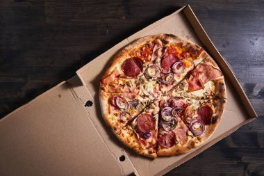 Tahta bir tahtanın üzerinde kartonda Pepperoni pizza, düz atış.