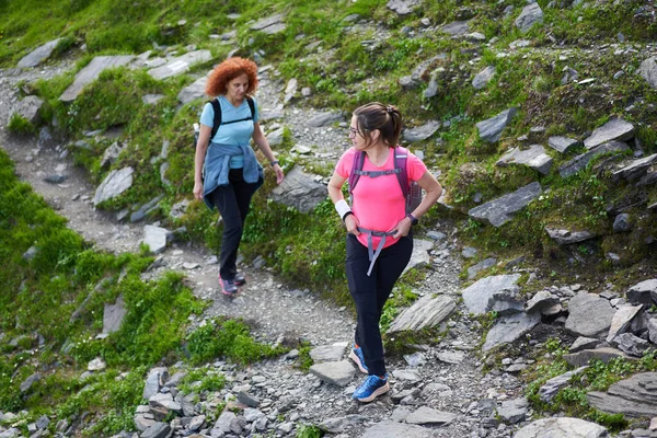 Duas Mulheres Caminhantes Com Mochilas Caminhando Uma Trilha Nas Montanhas — Fotografia de Stock