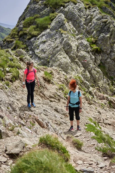 Duas Mulheres Caminhantes Com Mochilas Caminhando Uma Trilha Nas Montanhas Fotos De Bancos De Imagens