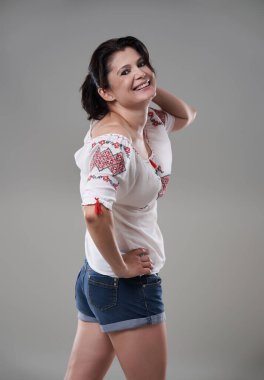 Gri arka planda günlük giysiler içindeki esmer kadını cezbediyor.