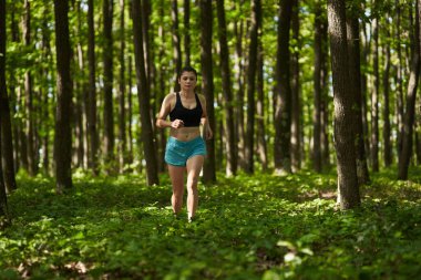Kadın koşucu ormanda yolda koşuyor