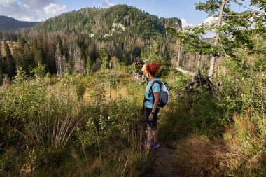 Sırt çantalı bir kadın dağlarda yürüyüş yapıyor.