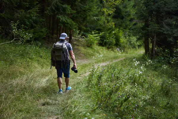 专业的自然摄影师 背着背包 带着相机在山林中远足 — 图库照片