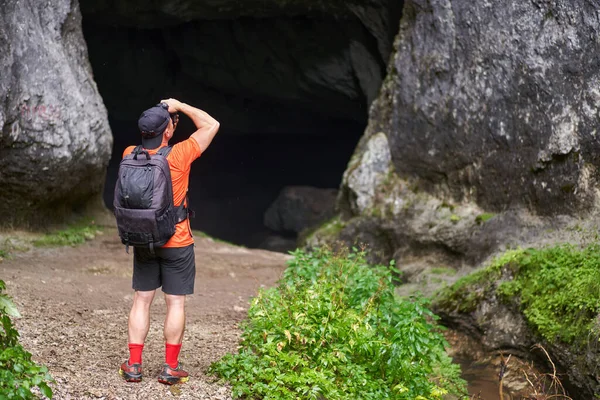 Hiker man with backpack exploring a cave in the limestone mountains