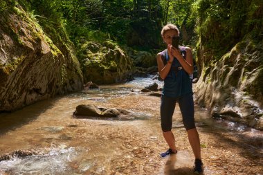 Sırt çantalı bir turist vadide telefonuyla fotoğraf çekiyor.
