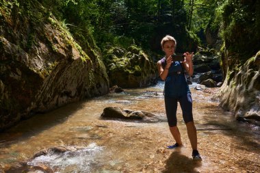 Sırt çantalı bir turist vadide telefonuyla fotoğraf çekiyor.
