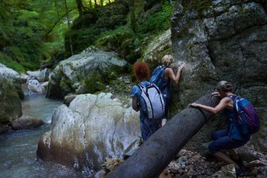 Sırt çantalı kadın yürüyüşçüler yemyeşil bir kanyonu ve nehri keşfediyorlar.