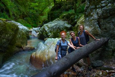 Sırt çantalı kadın yürüyüşçüler yemyeşil bir kanyonu ve nehri keşfediyorlar.