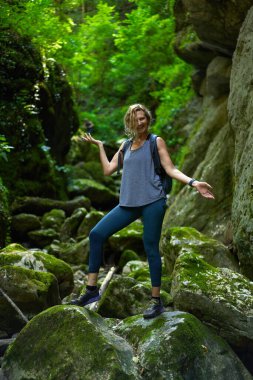 Sırt çantalı bir kadın gezgin, içinde nehir olan yemyeşil bir kanyonu keşfediyor.