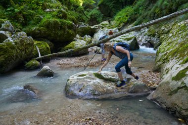 Sırt çantalı kadınlar, içinde nehir olan yemyeşil bir kanyonu keşfediyorlar.
