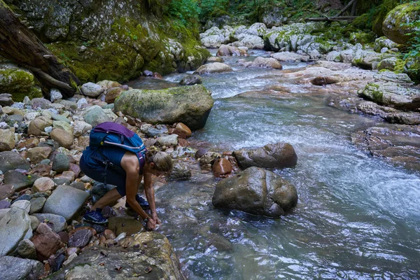 Sırt çantalı bir kadın gezgin, içinde nehir olan yemyeşil bir kanyonu keşfediyor.