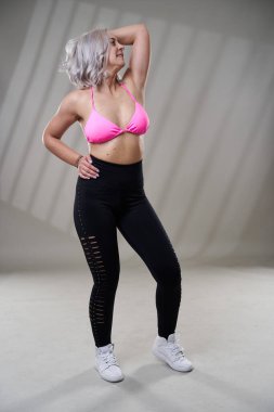 Şehir dansçısı gri arka planda dans hareketleri yapıyor. Stüdyo çekimi.