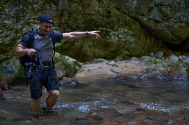 Sırt çantalı profesyonel doğa fotoğrafçısı bir vadide fotoğraf çekiyor.