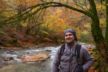 Sonbaharda renkli bir ormanda sırt çantalı bir yürüyüşçü.