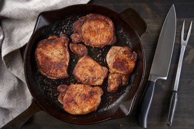 Tahtada kızarmış domuz filetosu pişirilmiş demir tava.