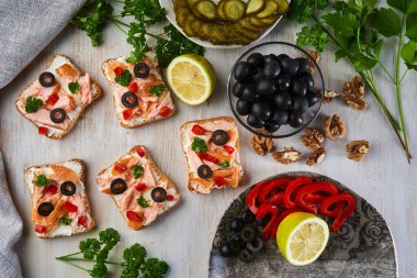 Tütsülenmiş somon, sebzeli ve zeytinli bruschetta ekmeği, Akdeniz aperatifi, ahşap bir tahtada.