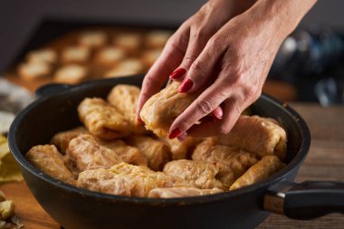 Kadınların elleri lahana rulolarını domuz eti ve pirinçle hazırlıyor, sarmale, geleneksel bir Romen yemeği.