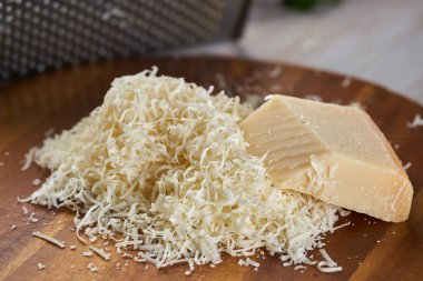 Parmesan bloğu rendelenmiş, yakın plan çekimde, ahşap kesim tahtasının üzerinde.