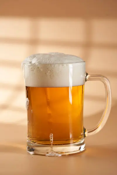 Pint of beer in various foam stages on beige background