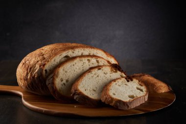 Koyu bir ahşap tahtada kesilmiş ev yapımı tahıllı ekmek.