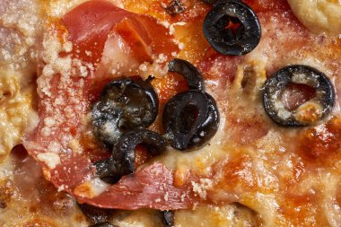 Eritilmiş parmesanlı, zeytin, pepperoni ya da jambon gibi içerikli bir pizzanın üzerine Macro shot.