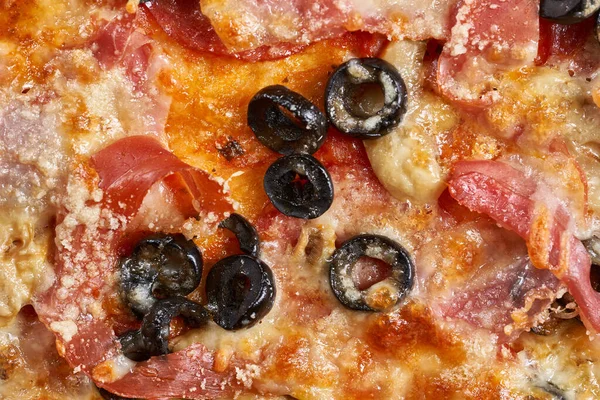 Eritilmiş parmesanlı, zeytin, pepperoni ya da jambon gibi içerikli bir pizzanın üzerine Macro shot.