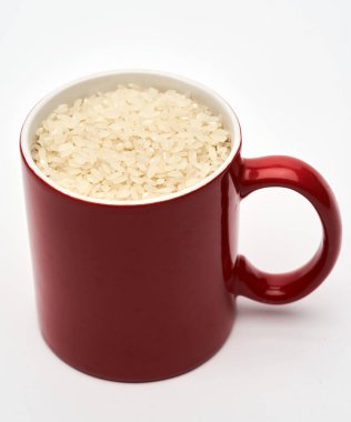 Kırmızı bardakta çiğ Çin pirinci, beyaz arka planda izole edilmiş.