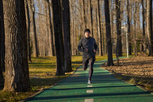 寒い晴れた冬の日に公園で走る成熟したアスリート — ストック写真
