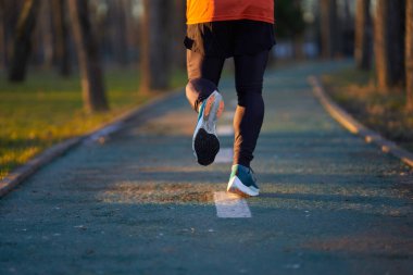 Parkta koşan spor ayakkabılarla koşucunun ayaklarının arkasından bak.