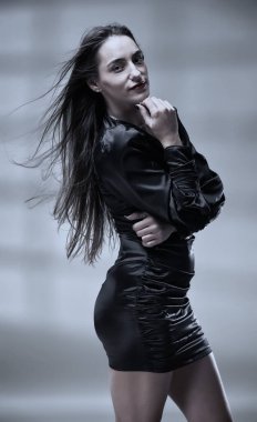 Saçları uçuşan, mini kırmızı siyah elbiseli, esmer, güzel bir kadının stüdyo çekimi.