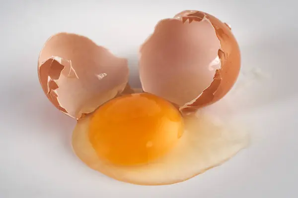 Broken chicken egg on white background, closeup shot