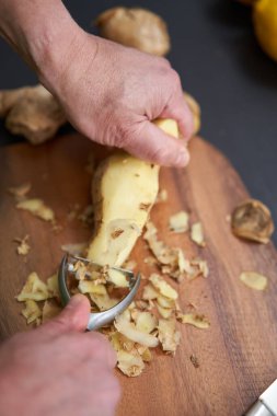 Adam ahşap bir tahtanın üzerinde büyük bir zencefil kökü soyup temizliyor.