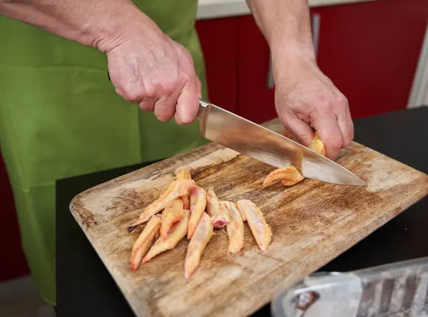 Man cook removing tips from chicken wings and cutting them in half for a recipe