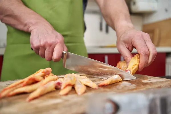 Man cook removing tips from chicken wings and cutting them in half for a recipe