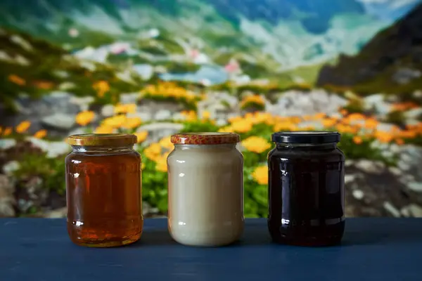 Various Honey Types Jars Wooden Board Beautiful Mountain View Flowers — Stock Photo, Image