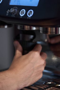 Erkek barmen, yüksek kaliteli kahve espresso yapmak için profesyonel aletler kullanıyor.