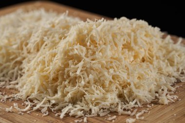 Parmesan bloğu siyah arkaplanda detaylı olarak rendelenmiş