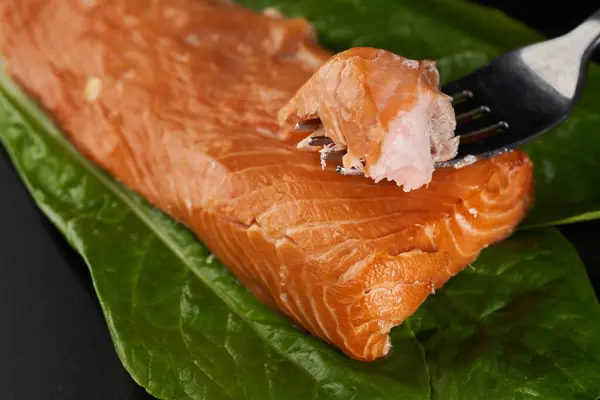 生菜叶上烟熏鲑鱼在黑色背景的特写下 图库图片