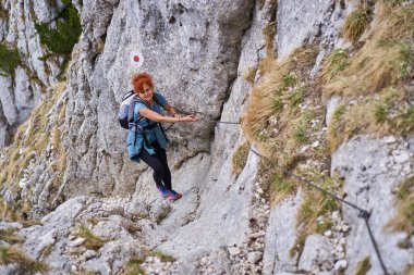 Dağcı kadın güvenlik hattında dik bir duvara tırmanıyor.