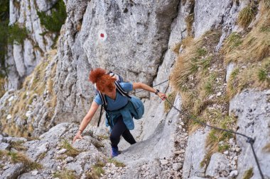 Dağcı kadın güvenlik hattında dik bir duvara tırmanıyor.